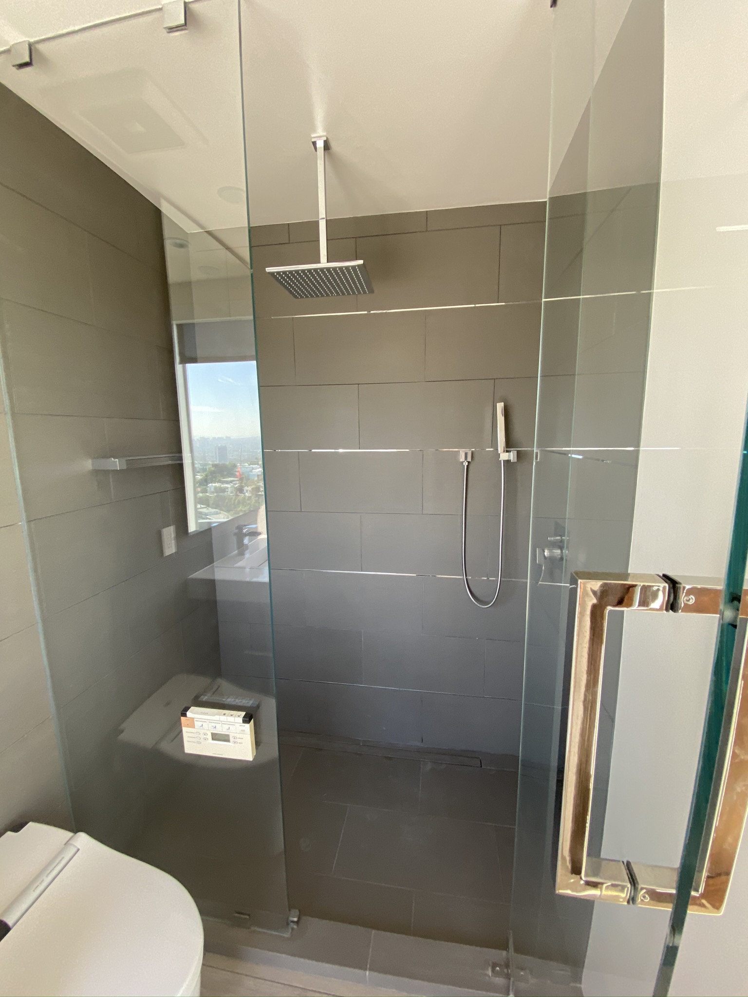 Glass-enclosed rain shower with large-format tile by RMK Builders