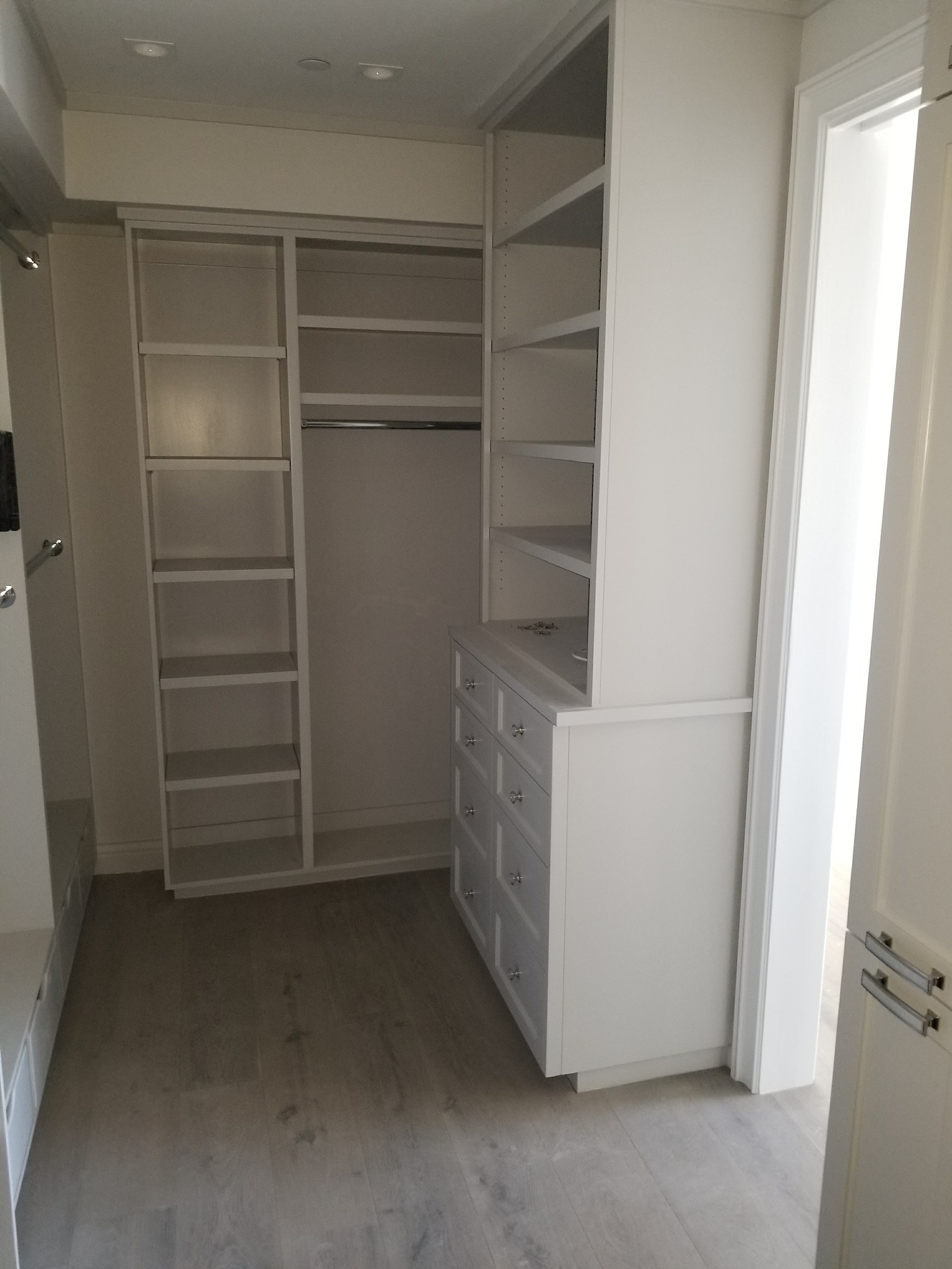 Custom white walk-in closet with built-in shelving and drawers by RMK Builders