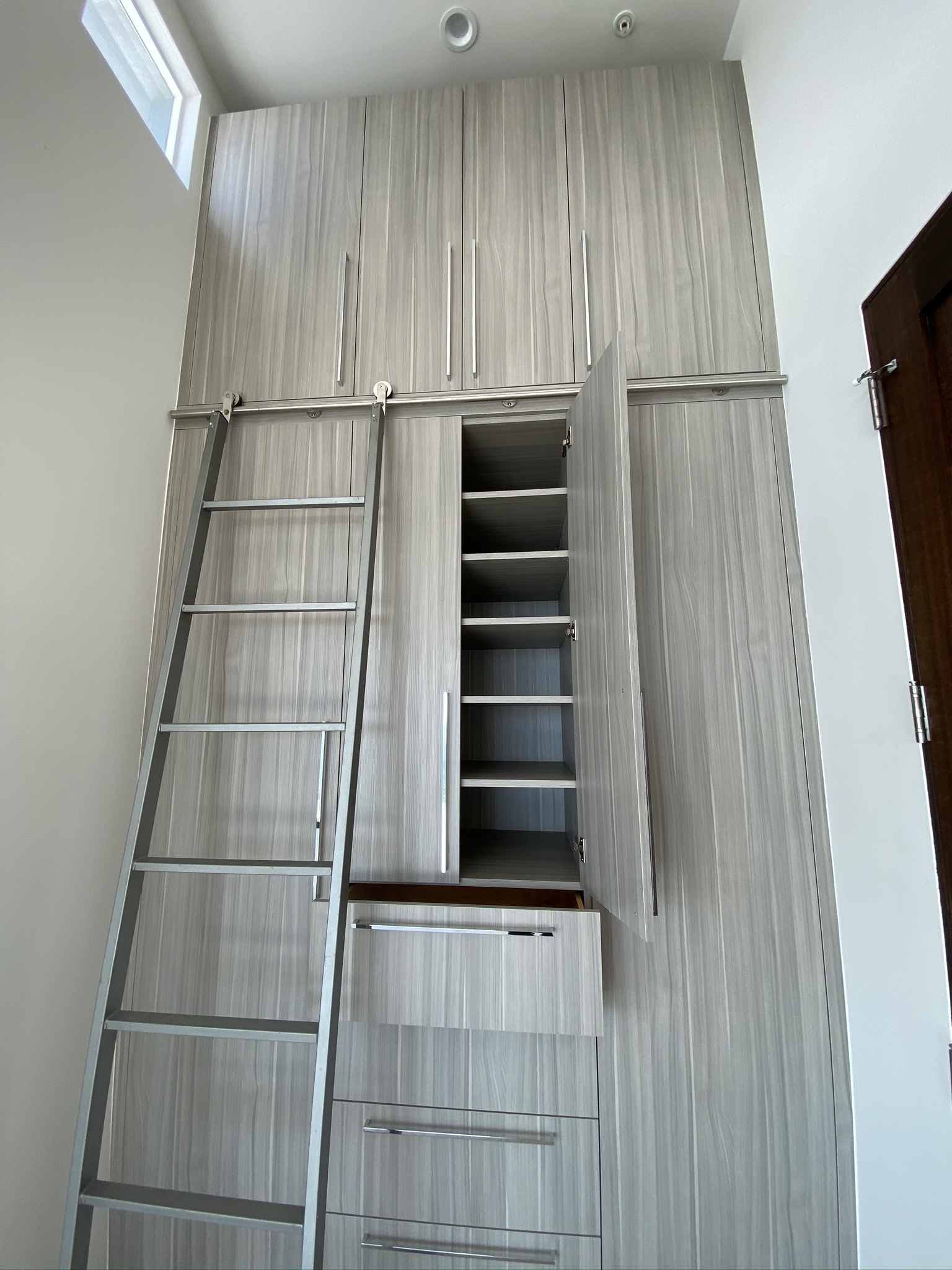 Floor-to-ceiling custom cabinetry with a rolling ladder by RMK Builders