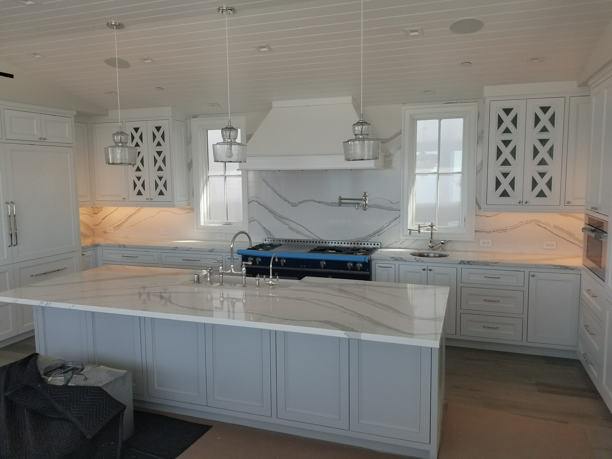 Custom white kitchen with a marble waterfall island and range hood by RMK Builders