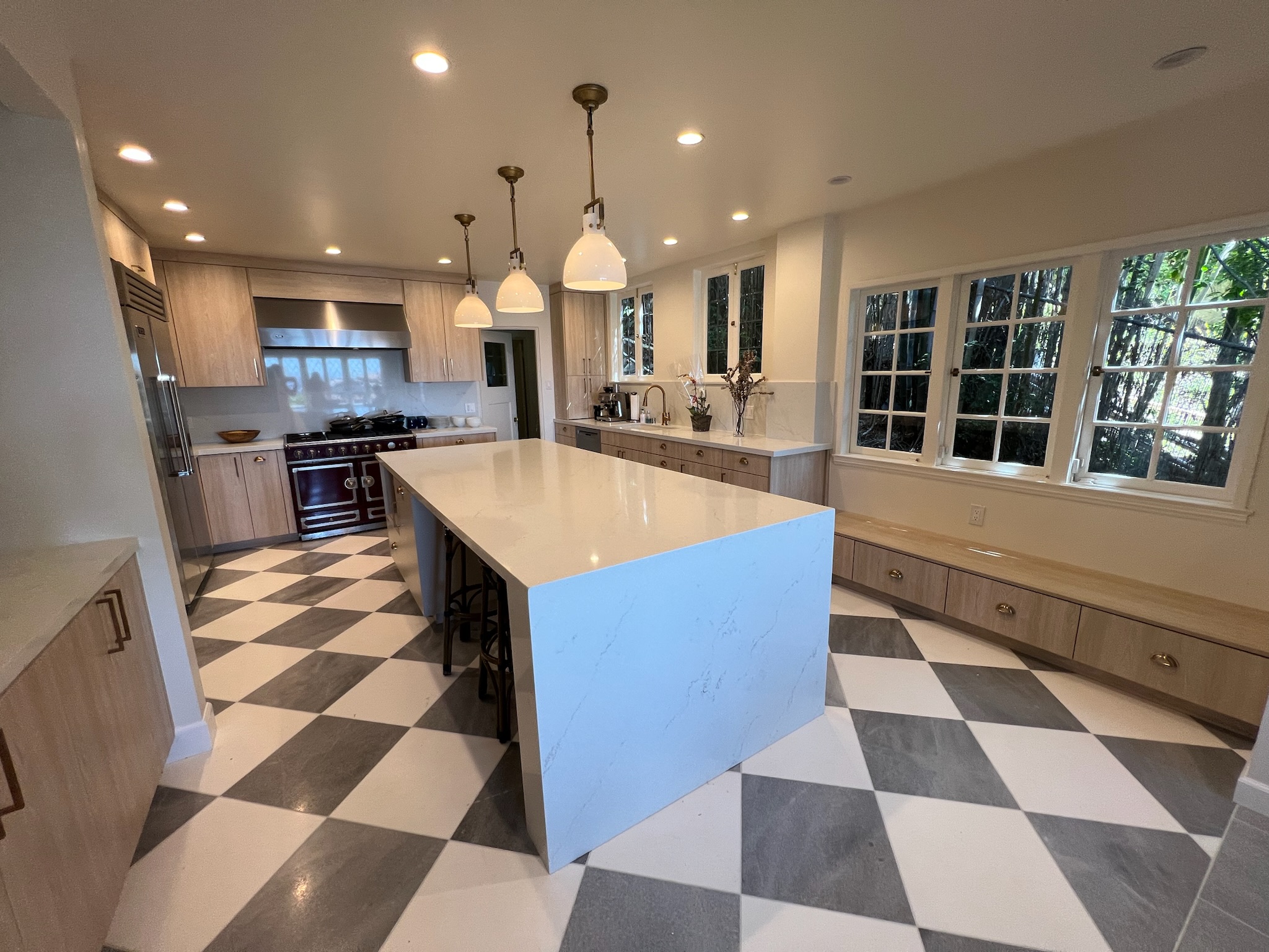 Traditional country inspired kitchen with checkered marble floors, custom slab cabinetry and quartz islands