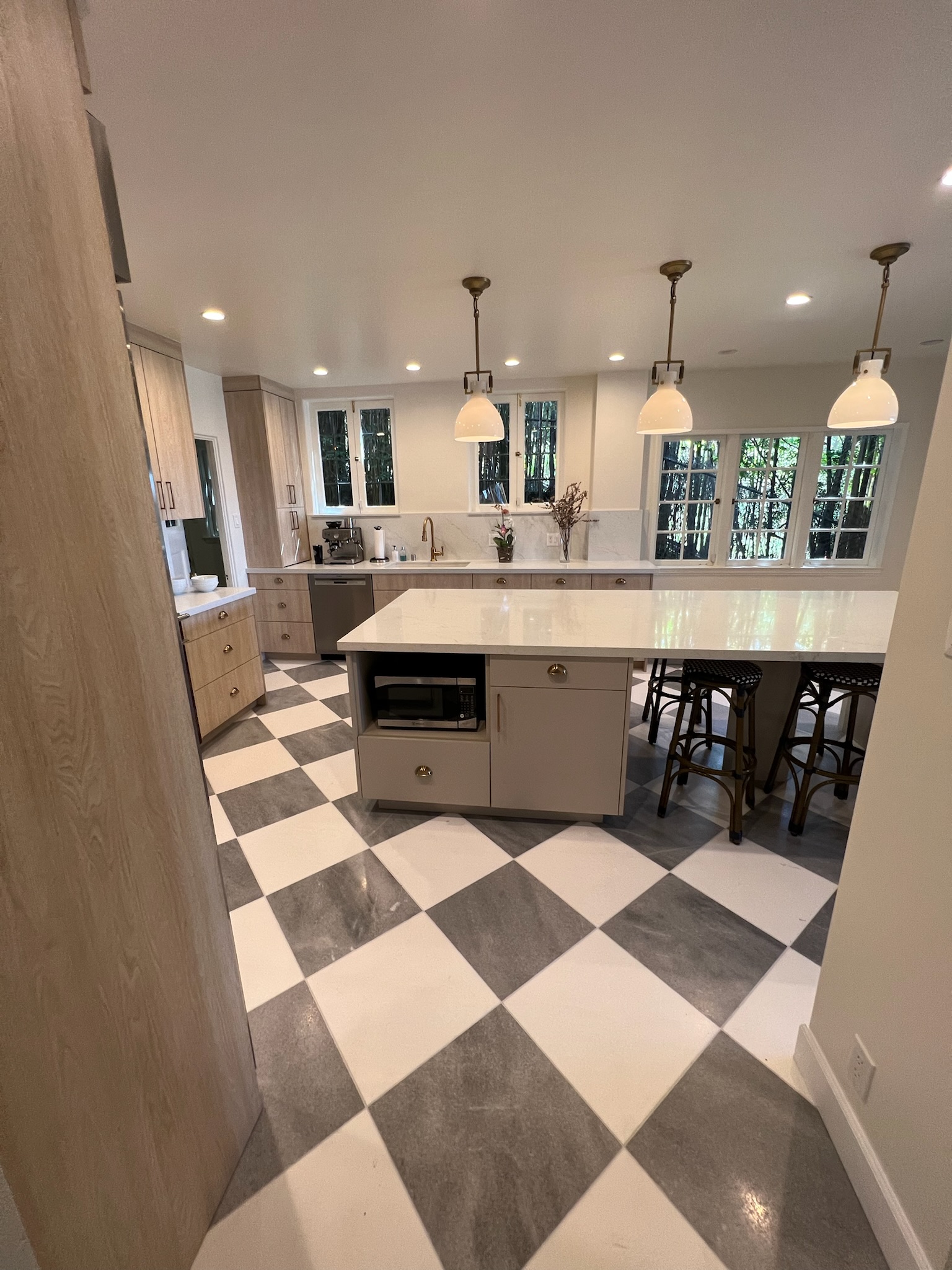 Traditional country inspired kitchen with checkered marble floors, custom slab cabinetry and quartz islands